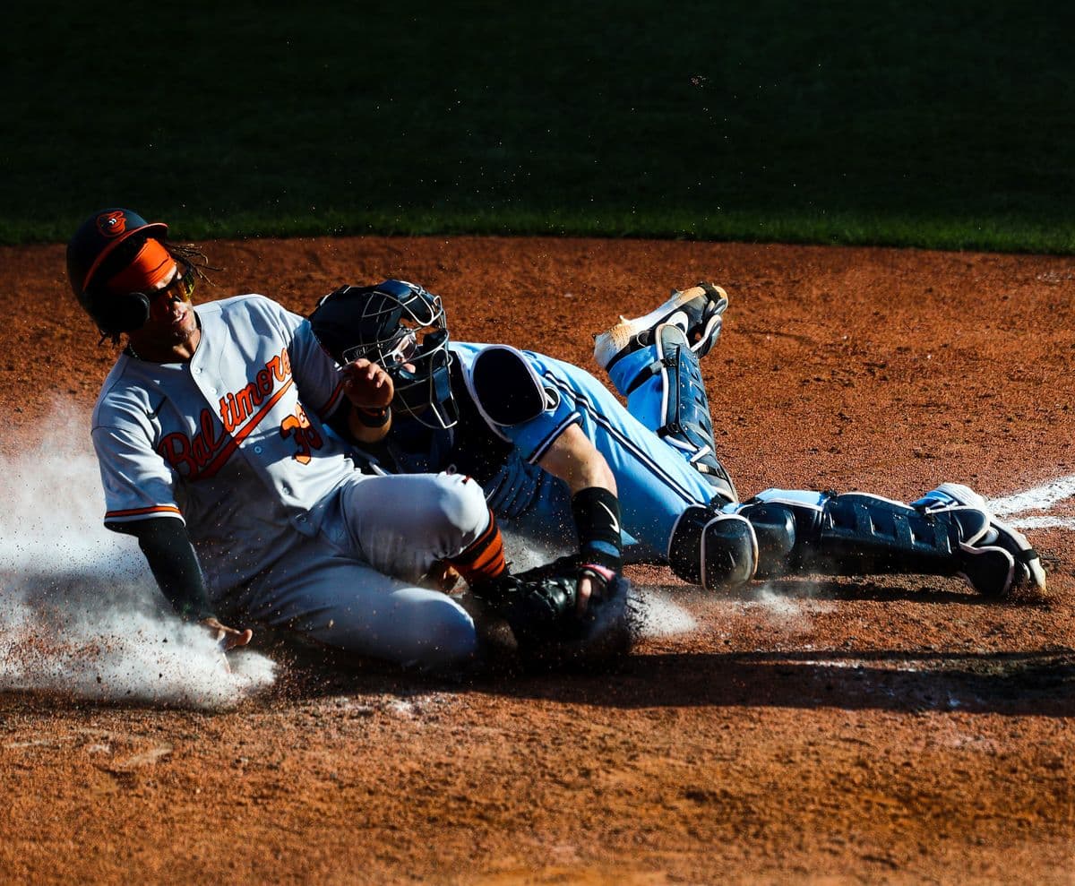 BUFFALO, NEW YORK - AUGUST 31: Mason Williams #38 of the Baltimore Orioles is tagged out at home plate by Danny Jansen #9 of the Toronto Blue Jays on a throw from Teoscar Hernandez #37 of the Toronto Blue Jays during the tenth inning at Sahlen Field on August 31, 2020 in Buffalo, New York. The Blue Jays are the home team and are playing their home games in Buffalo due to the Canadian governmentâs policy on coronavirus (COVID-19). (Photo by Bryan M. Bennett/Getty Images)
